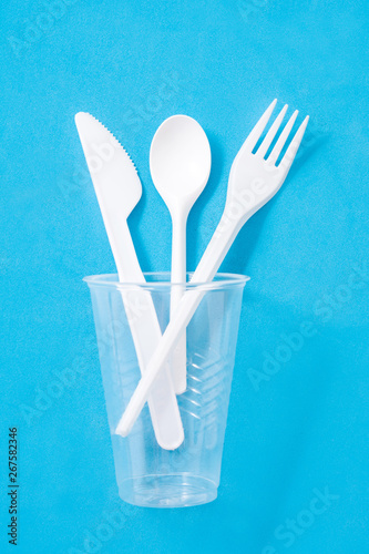 Disposable plastic cutlery on blue background. Top view
