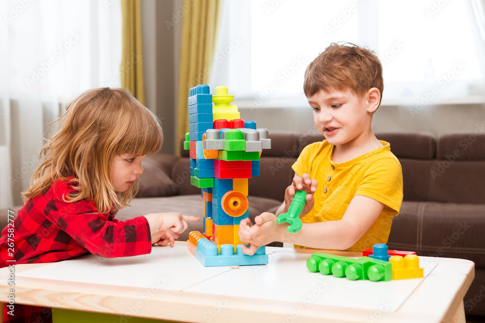 Little boy playing with lots of colorful plastic blocks constructor and builds the robot indoor. 