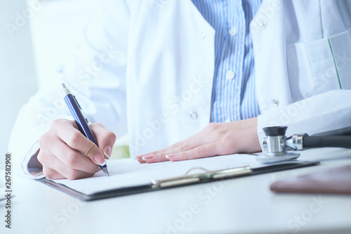 Female medicine doctor hand holding silver pen writing something on clipboard closeup.. Ward round  patient visit check  medical calculation and statistics concept.