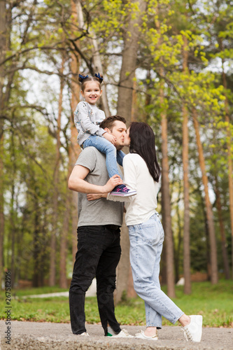 Happy family: mother, father and little daughter outdoor. Parents giving child © ulza