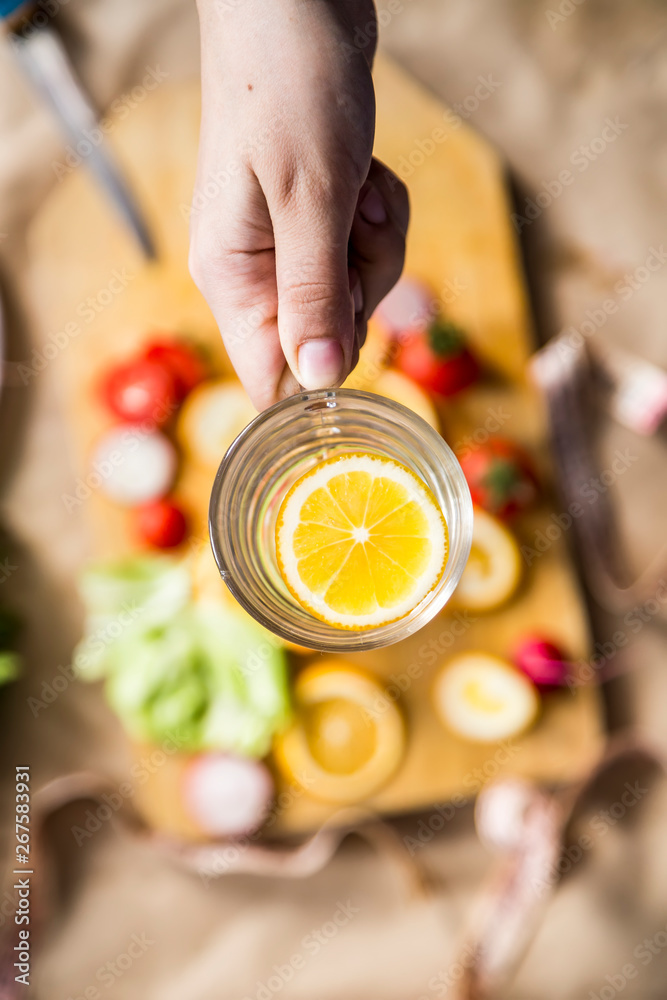 Woman's hand holding a glass of fresh lemon water Woman's hand holding a glass of fresh lemon water