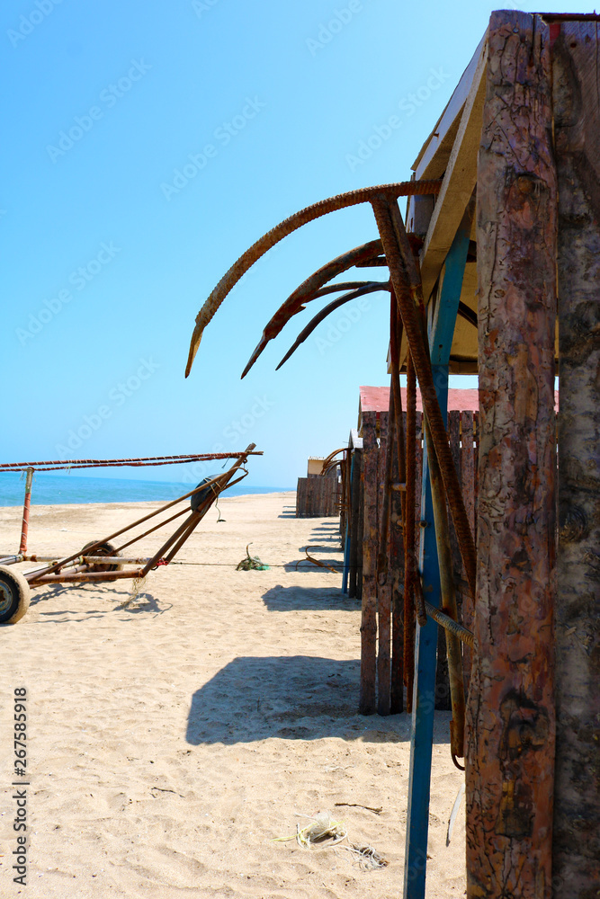 Reed huts on beach and rusty anchors