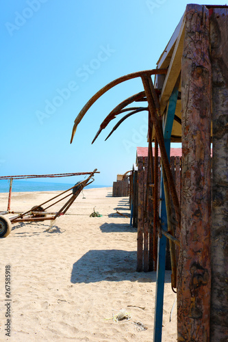 Reed huts on beach and rusty anchors