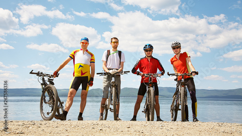 group of cyclists on the shore of a mountain lake. man outdoors. mountain bike.