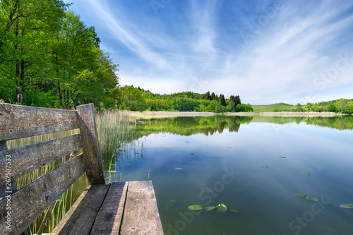 bench on the footbridge over the lake during a sunny day. Spring calm landscape. Masuria, Poland