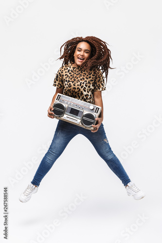 Image of happy african american woman smiling and holding vintage boombox with cassette tape