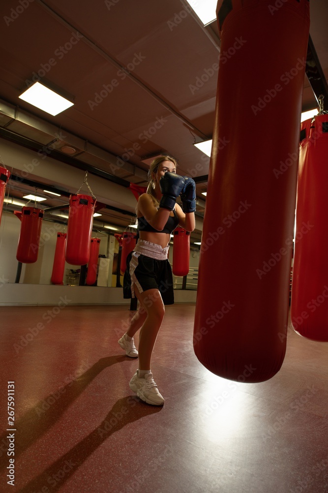 Young blonde in boxing gloves in a gym