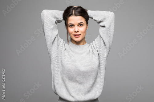 Smiling woman wearing gray sweater standing against isolated gray background. © F8  \ Suport Ukraine