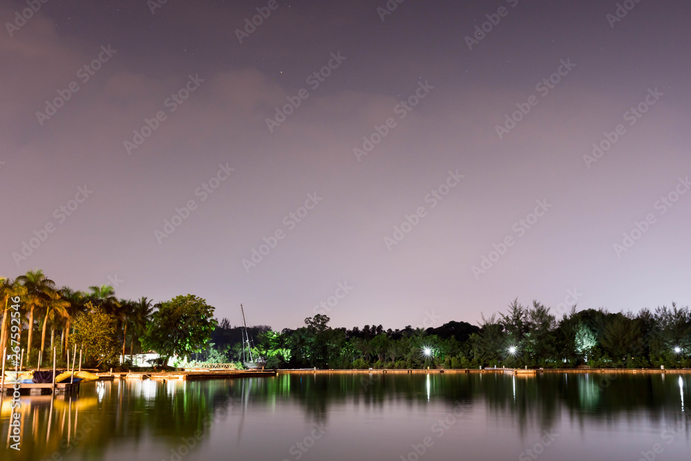 Horizontal view of lake and nature during dusk with night stars and smooth reflection on waters