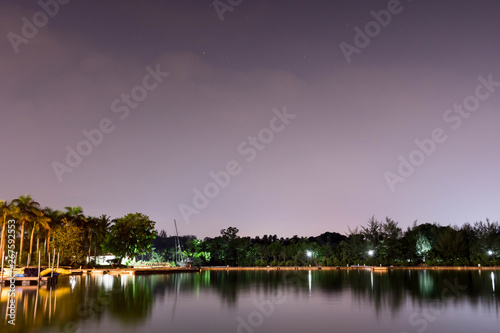 Horizontal view of lake and nature during dusk with night stars and smooth reflection on waters