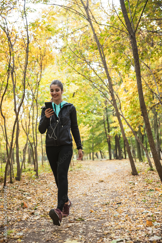 Young pretty fitness woman outdoors in the park using mobile phone. Young pretty fitness woman outdoors in the park using mobile phone.