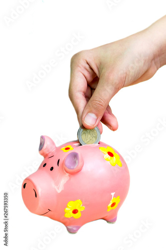 Girl put coin two euro into pink piggy bank. Hands close-up.
