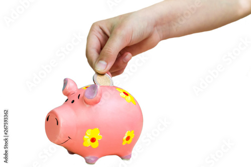 Girl put coin two euro into pink piggy bank. Hands close-up.
