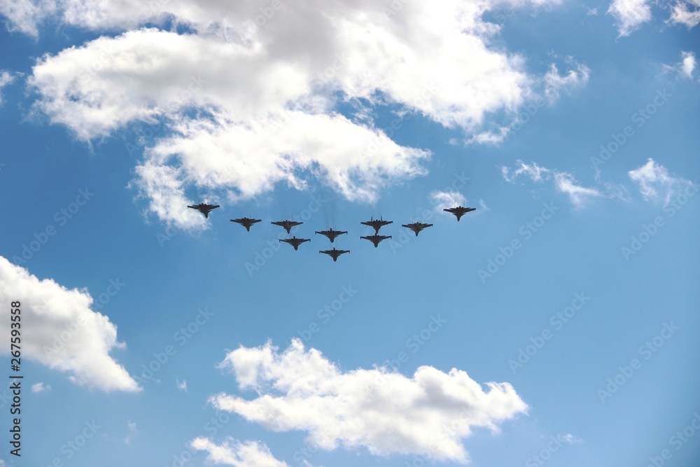 Ten planes in a blue sky with clouds on a Sunny day, selective focus. A group of ten aircraft in a blue sky with white clouds.