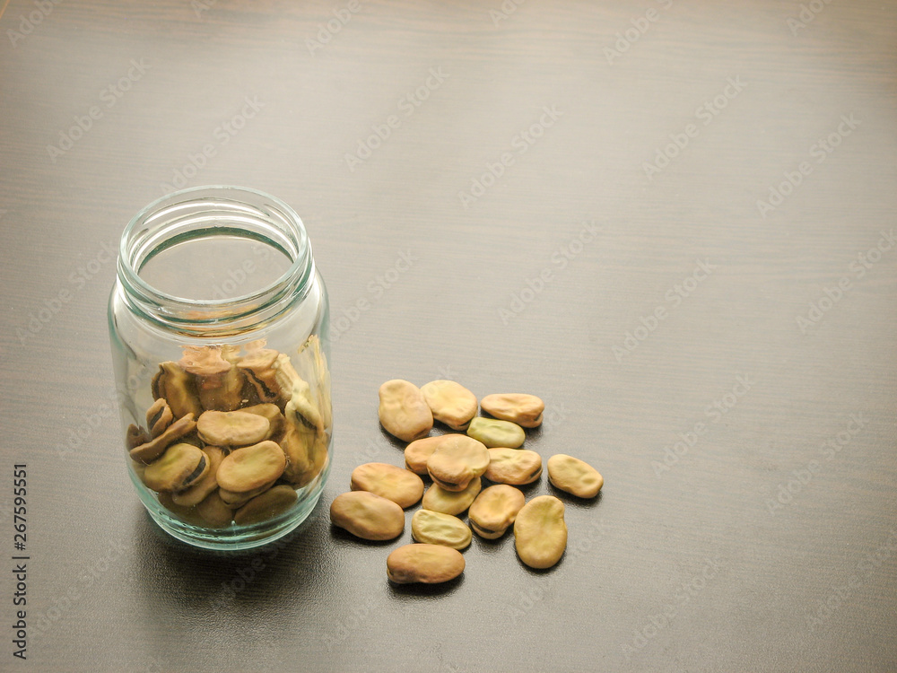 Broad beans (Vicia faba) in a glass jar on the wooden table. Broad beans (Vicia faba) in a glass jar on the wooden table.