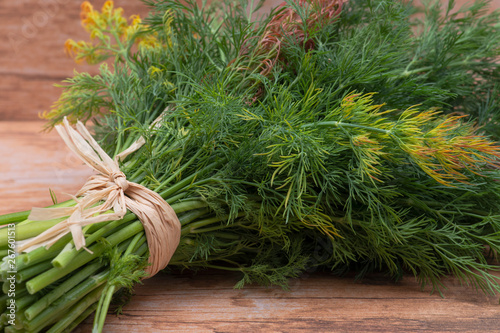 Fresh Organic Dill tied with a straw isolated on wooden background.