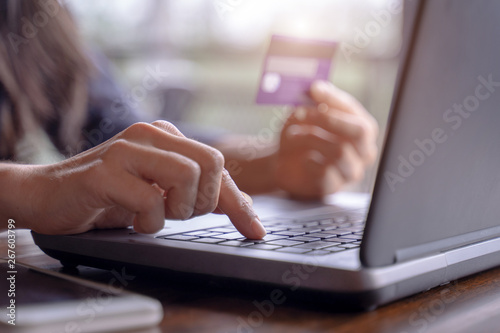 Woman's hands holding credit card and typing on the keyboard of laptop for shopping online. Pays for purchase