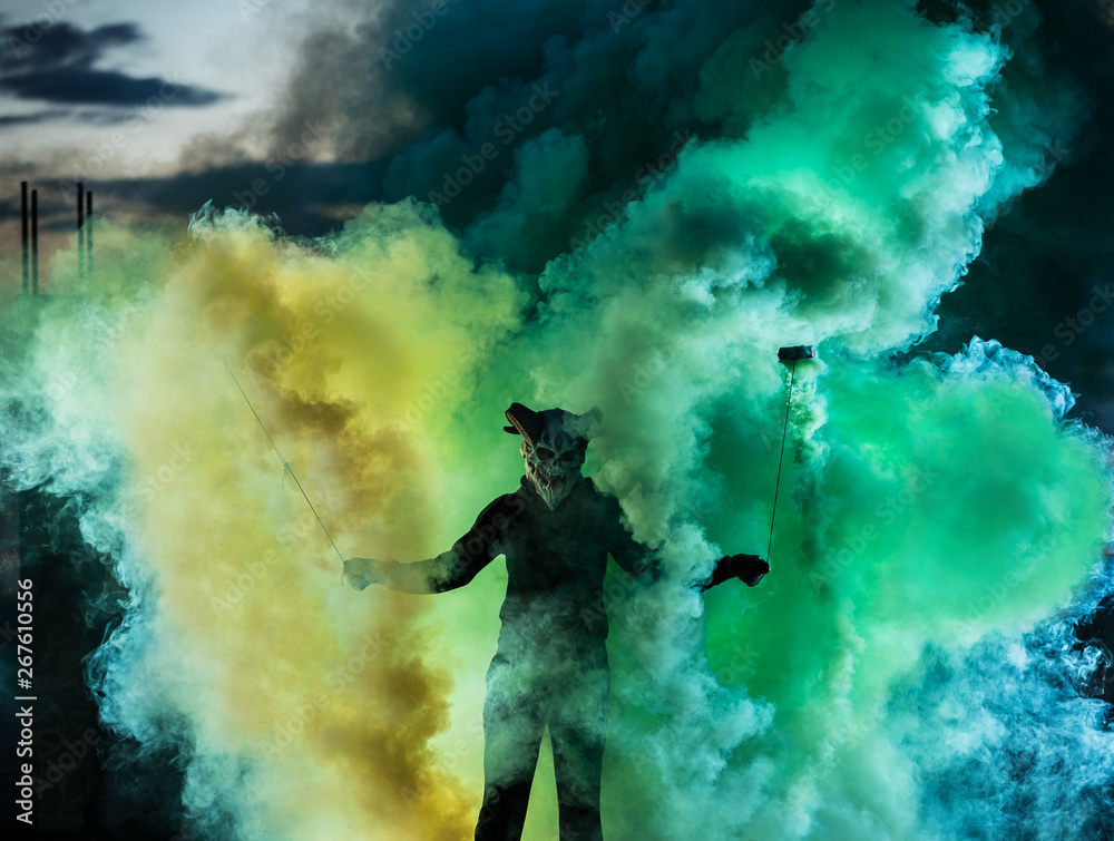 Fototapeta premium Devil with scary mask surrounded by coloured smoke