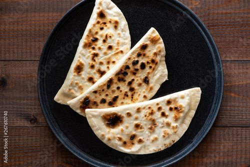 Flatbread on a black plate  wooden background  top view  copy space.