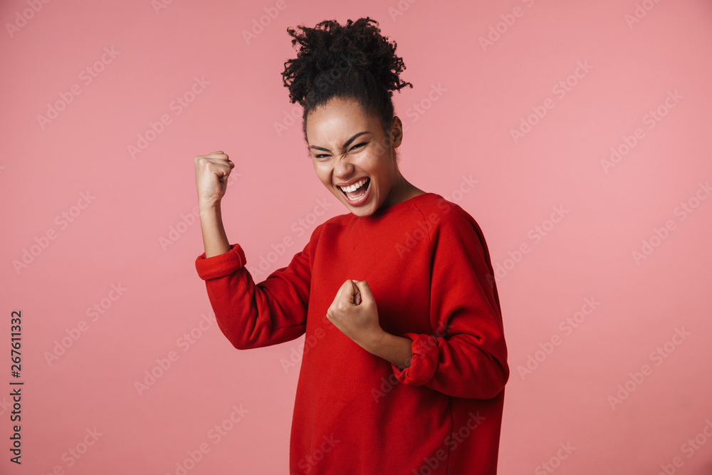 Beautiful young excited african woman posing isolated over pink wall background make winner gesture. Beautiful young excited african woman posing isolated over pink wall background make winner gesture.
