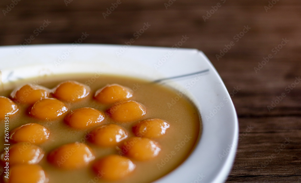 Biji salak on wood background. Biji salak is sweet potato dumplings with coconut sauce. Popular dessert in Indonesia or to break the fast. Biji salak on wood background. Biji salak is sweet potato dumplings with coconut sauce. Popular dessert in Indonesia or to break the fast.