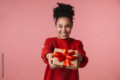 Amazing happy excited young african woman posing isolated over pink wall background holding present box. © Drobot Dean
