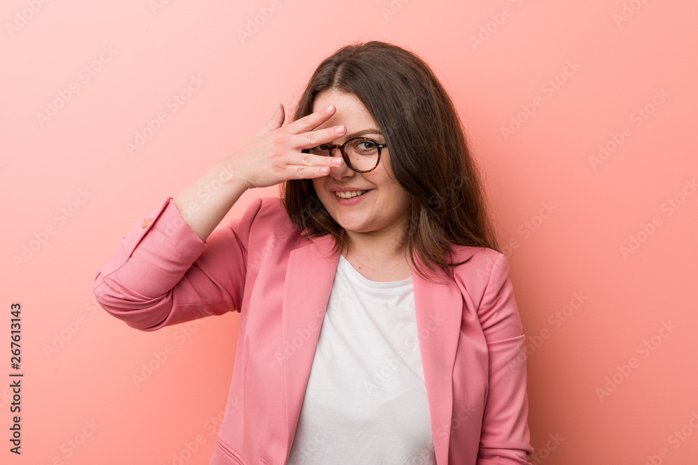 Young plus size business caucasian woman blink at the camera through fingers, embarrassed covering face. Young plus size business caucasian woman blink at the camera through fingers, embarrassed covering face.