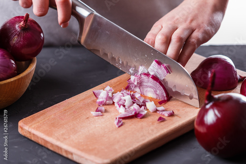 young woman in a gray aprons cuts red onion photo