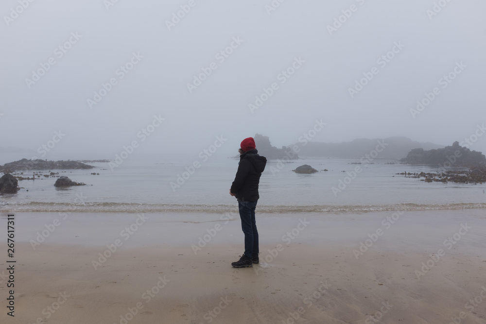 Woman looking at ocean back to camera, cold day Woman looking at ocean back to camera, cold day