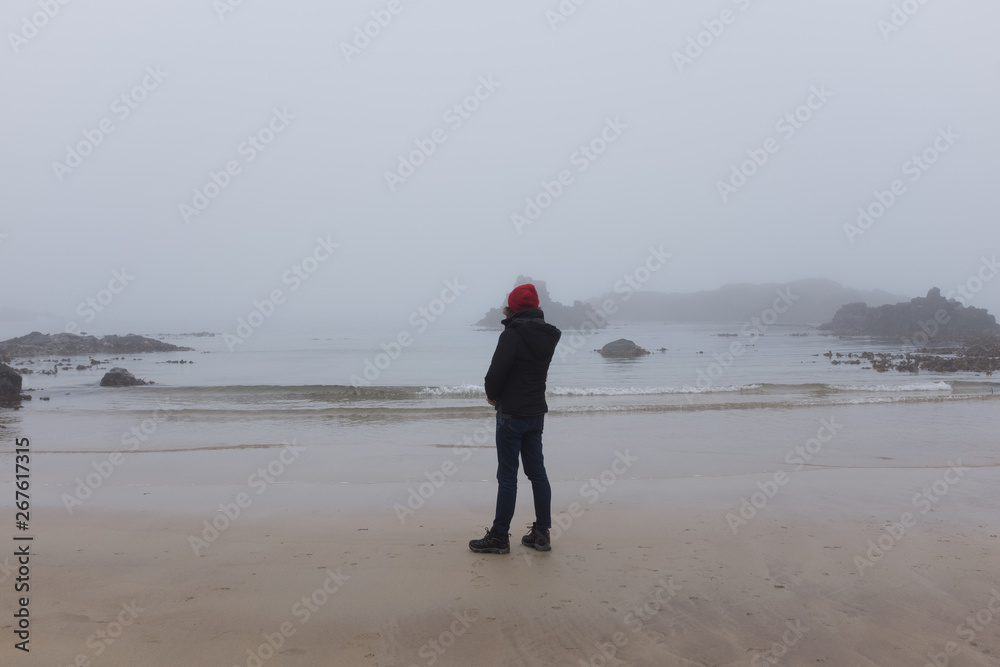 Woman looking at ocean back to camera, cold day Woman looking at ocean back to camera, cold day