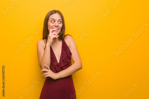 Young elegant woman wearing a dress relaxed thinking about something looking at a copy space