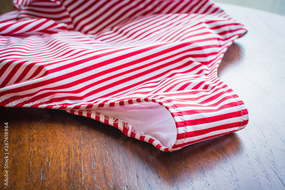 Fototapeta premium Female swimsuit in red strip for bathing on wooden table.