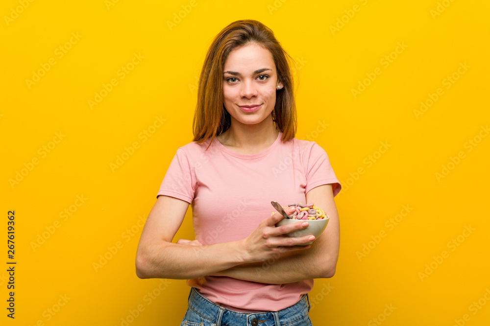 Obraz premium Young woman holding a cereals bowl smiling confident with crossed arms.