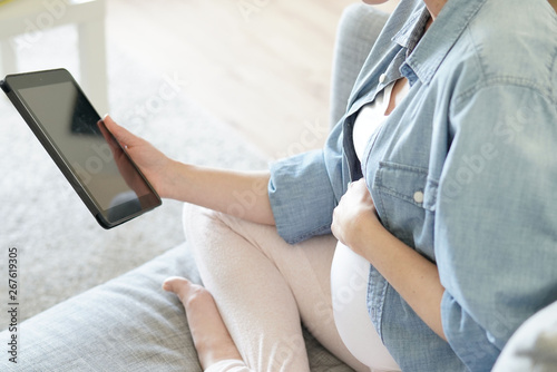 Pregnant woman using digital tablet  relaxing in couch