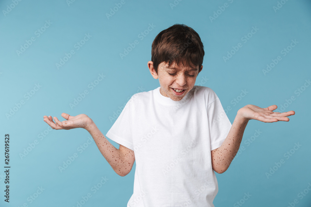 Portrait closeup of candid beautiful boy 10-12y with freckles wearing white casual t-shirt smiling and gesturing hands aside Portrait closeup of candid beautiful boy 10-12y with freckles wearing white casual t-shirt smiling and gesturing hands aside