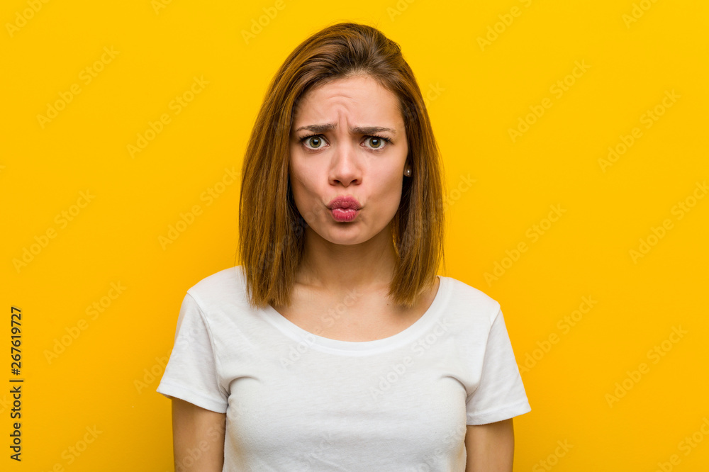 Young natural caucasian woman blows cheeks, has tired expression. Facial expression concept. Young natural caucasian woman blows cheeks, has tired expression. Facial expression concept.