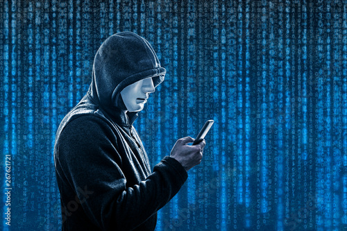 Hooded hacker with mask holding smartphone