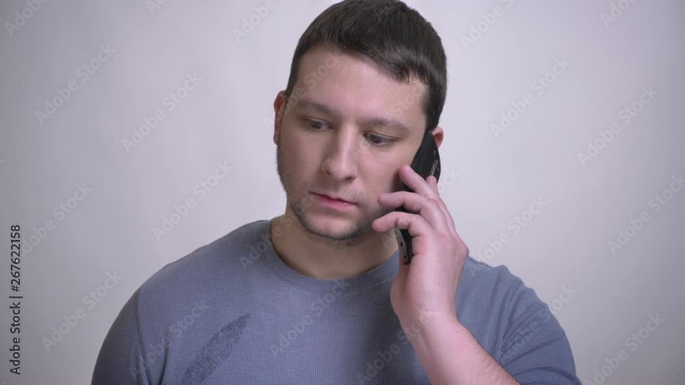 Closeup portrait of adult attractive caucasian man having a phone call with background isolated on white Closeup portrait of adult attractive caucasian man having a phone call with background isolated on white