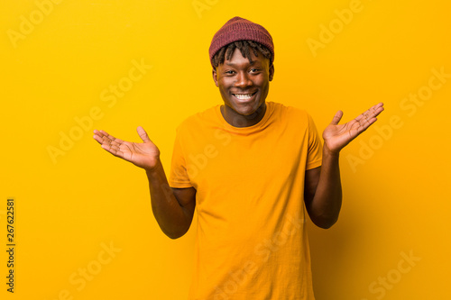 Photos Young black man wearing rastas over yellow background doubting and shrugging him shoulders in questioning gesture