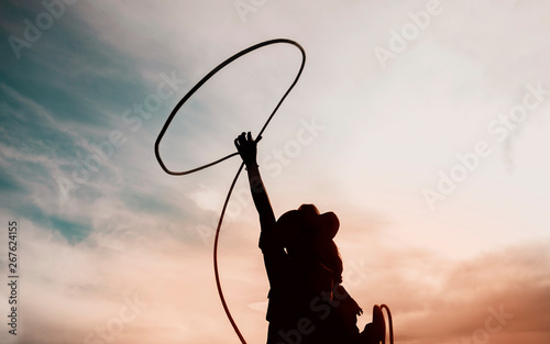 pretty Chinese cowgirl throwing the lasso in a horse paddock photo