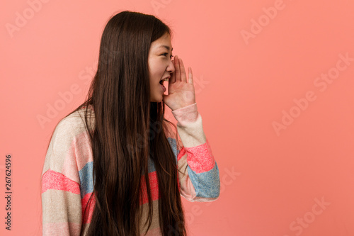 Young cool chinese woman shouting and holding palm near opened mouth.
