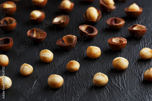 Purified and shell repeats macadamia nuts on black textural stone background. Healthy eating concept