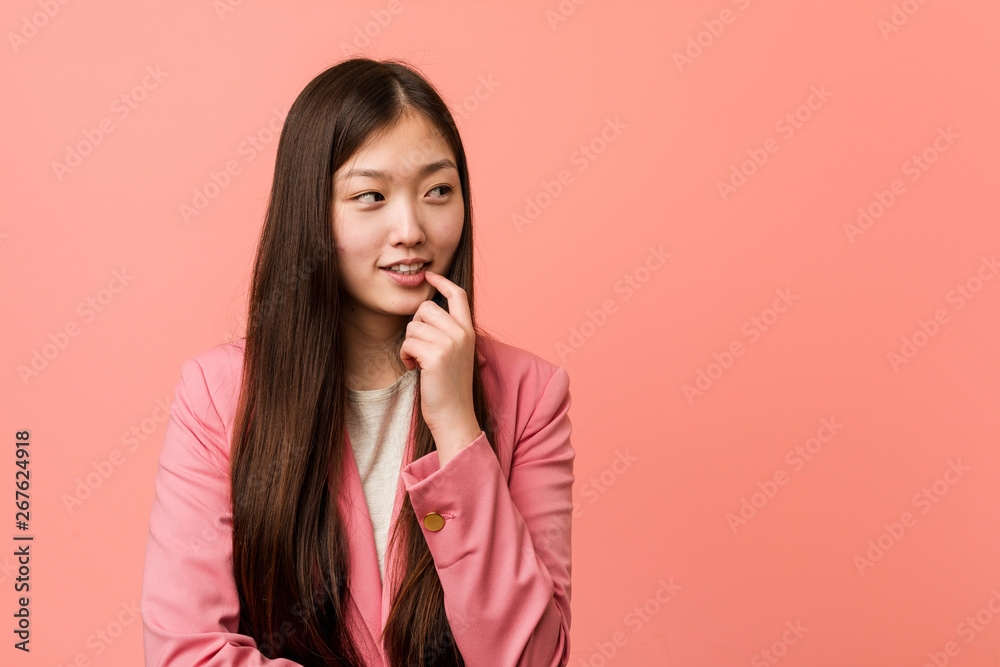 Young business chinese woman wearing pink suit relaxed thinking about something looking at a copy space. Young business chinese woman wearing pink suit relaxed thinking about something looking at a copy space.