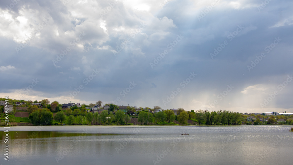 Rain over a small lake, with a farmland royal field