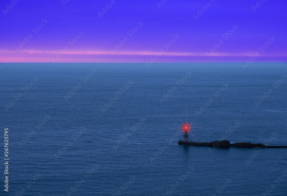 red luminous signal for navigation, entrance to the harbor at sunset
