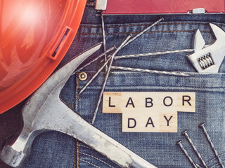 LABOR DAY. Wrench, nails, stylish jeans and wooden letters of the alphabet. Top view, close-up. Preparations for celebration. Congratulations for relatives, friends and colleagues