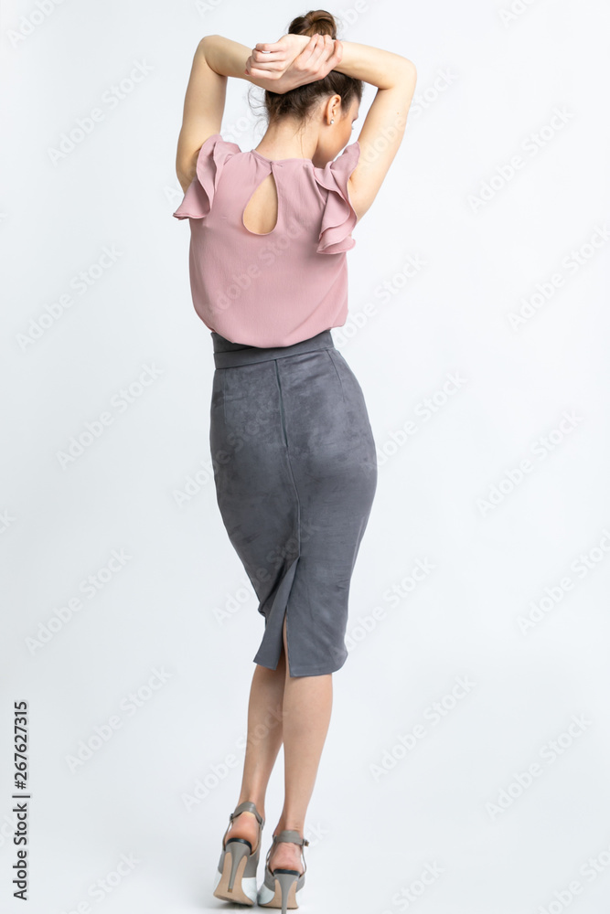 Model in purple blouse, grey suede skirt with belt, white heeled sandals isolated on white background. Model in purple blouse, grey suede skirt with belt, white heeled sandals isolated on white background.