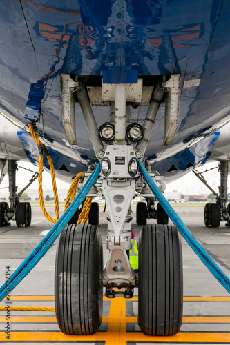 The front landing gear of the aircraft standing on the refueling at the airport.