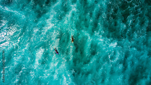 Surfers waiting for a good wave on sunny day. Muriwai Beach, Auckland, New Zealand photo