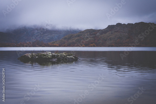 lake between mountains with low clouds